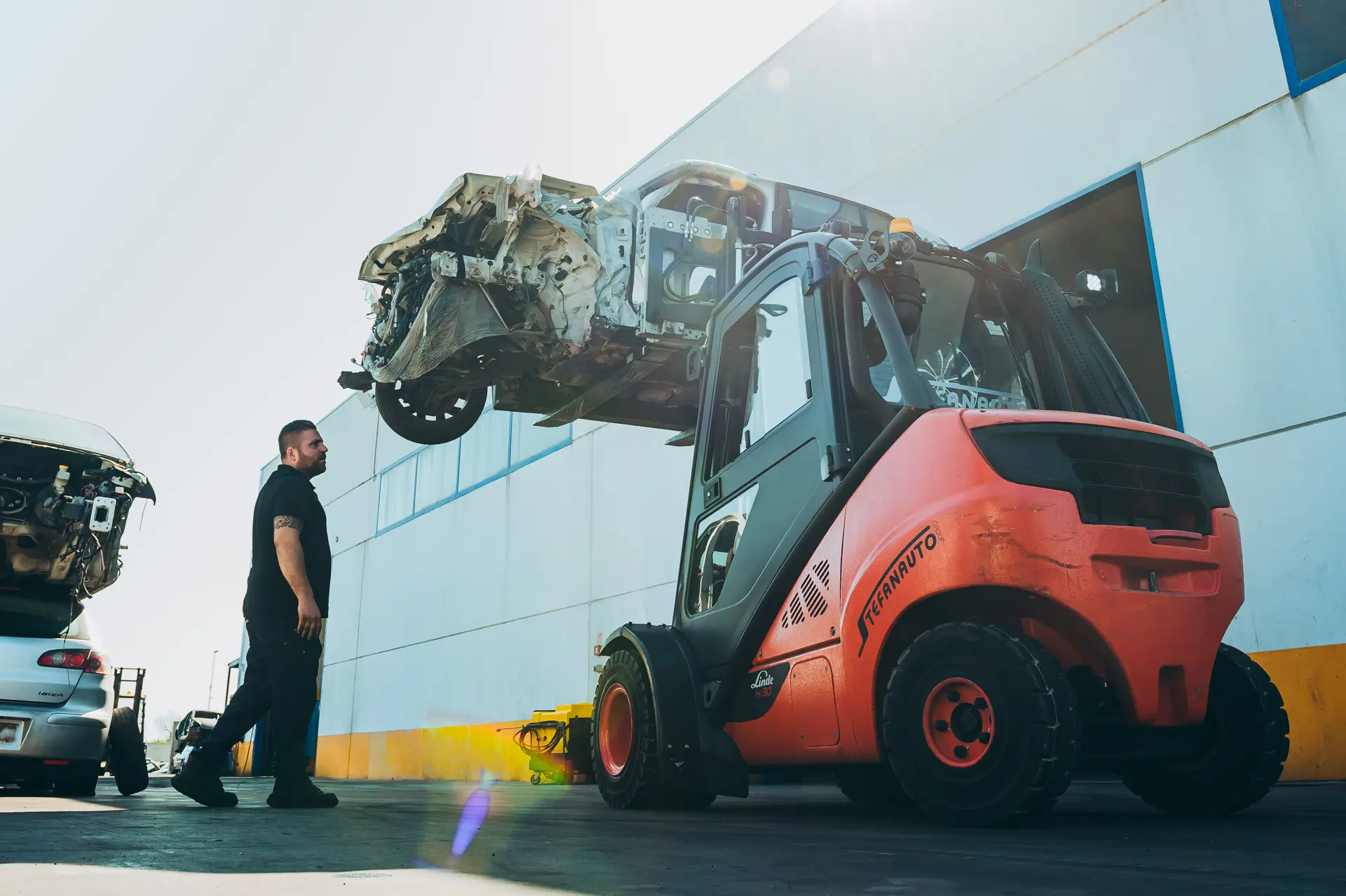 Muletto Stefanauto che solleva un'auto incidentata davanti allo stabilimento